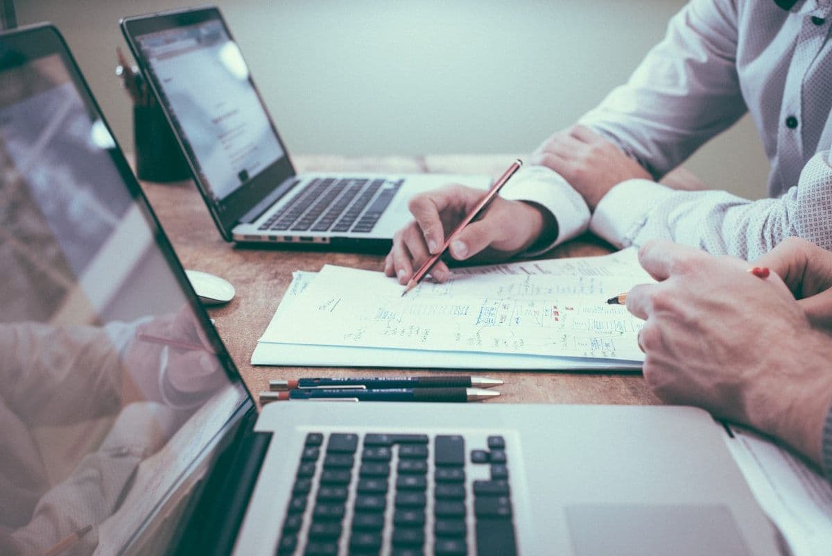 Professional reviewing financial documents at a modern desk setup with laptop and paperwork — back-office finance operations context