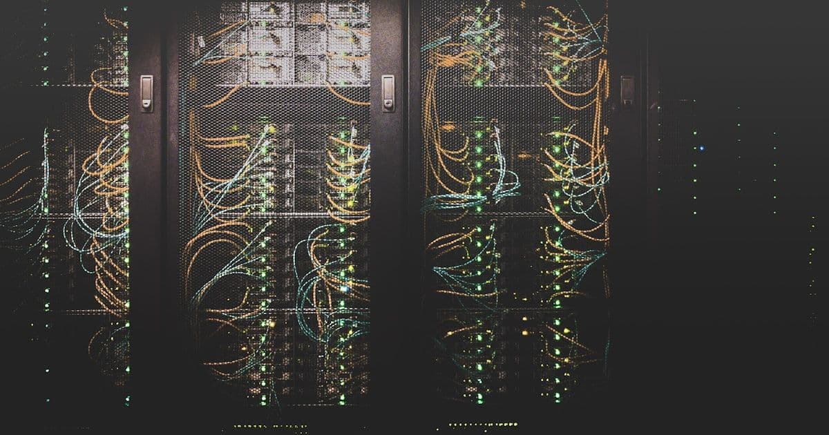 Fiber optic cables glowing in blue light inside a network distribution panel